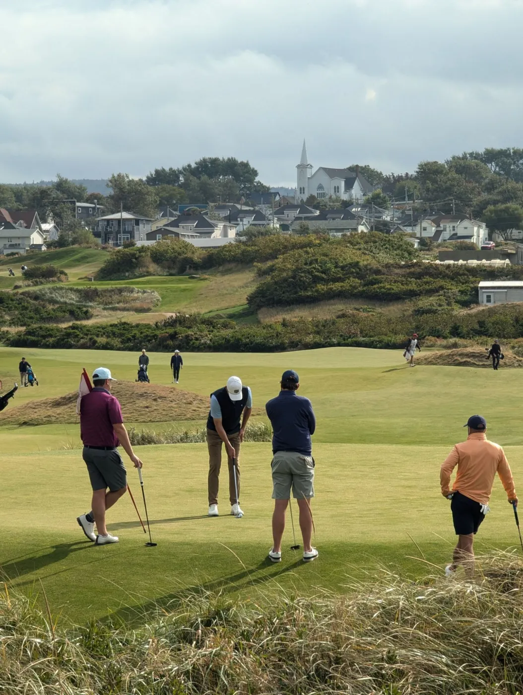 Four golfers on a putting green