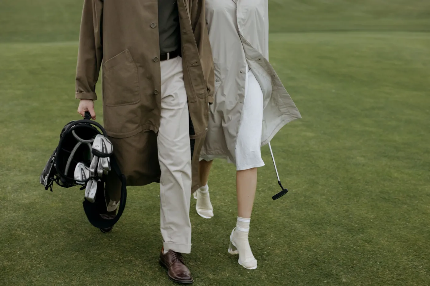 Two golfers walking the fairway with a bag and putter