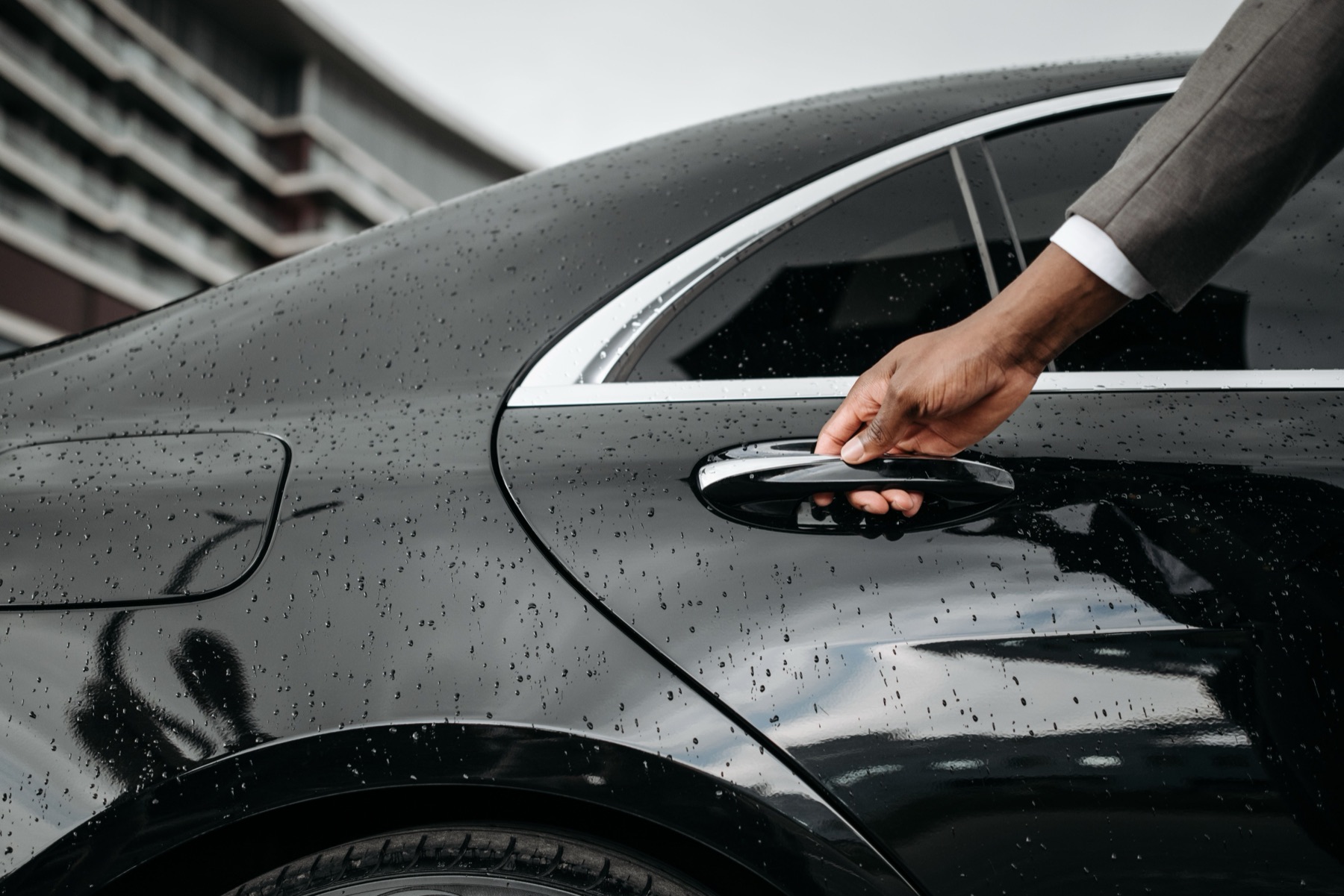 Chauffeur opening the car door handle for a New Class Limo client