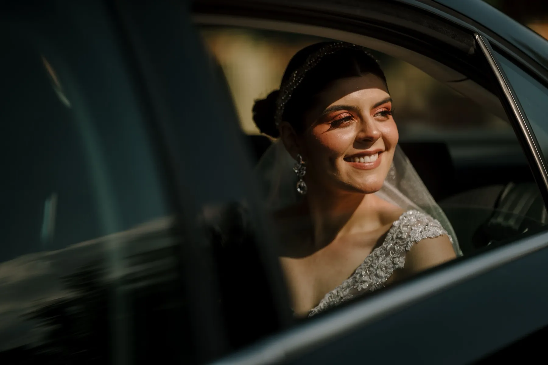 Bride smiling from the back seat of a car